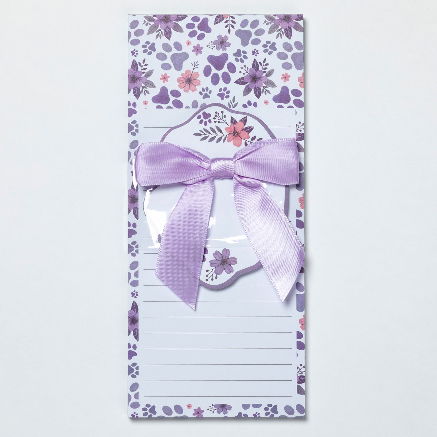 Notepad with floral design and a purple bow on a white background