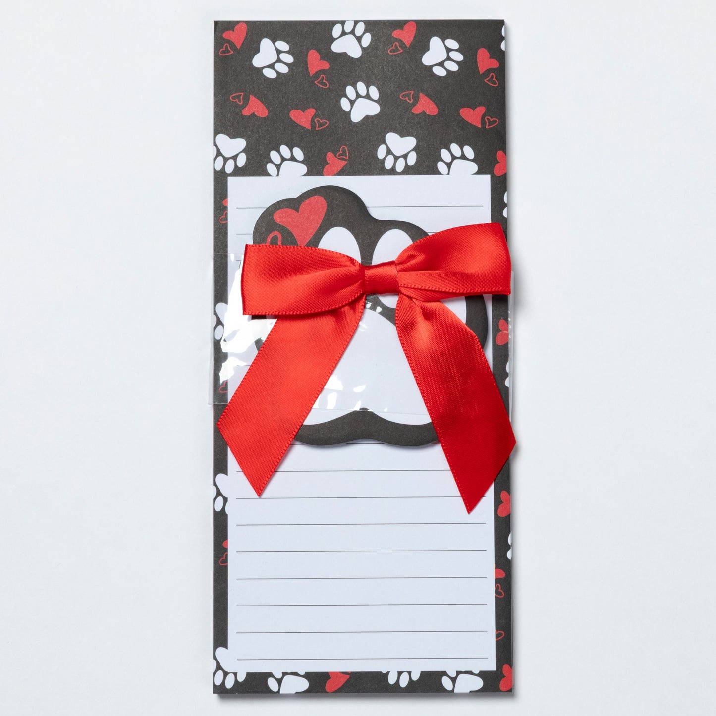 Notepad with a red ribbon on a black background with paw and heart patterns