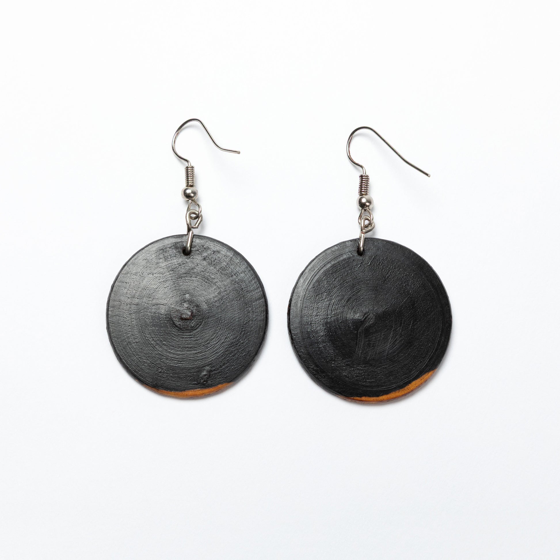 Black circular wood earrings on a white background