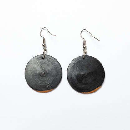 Black circular wood earrings on a white background