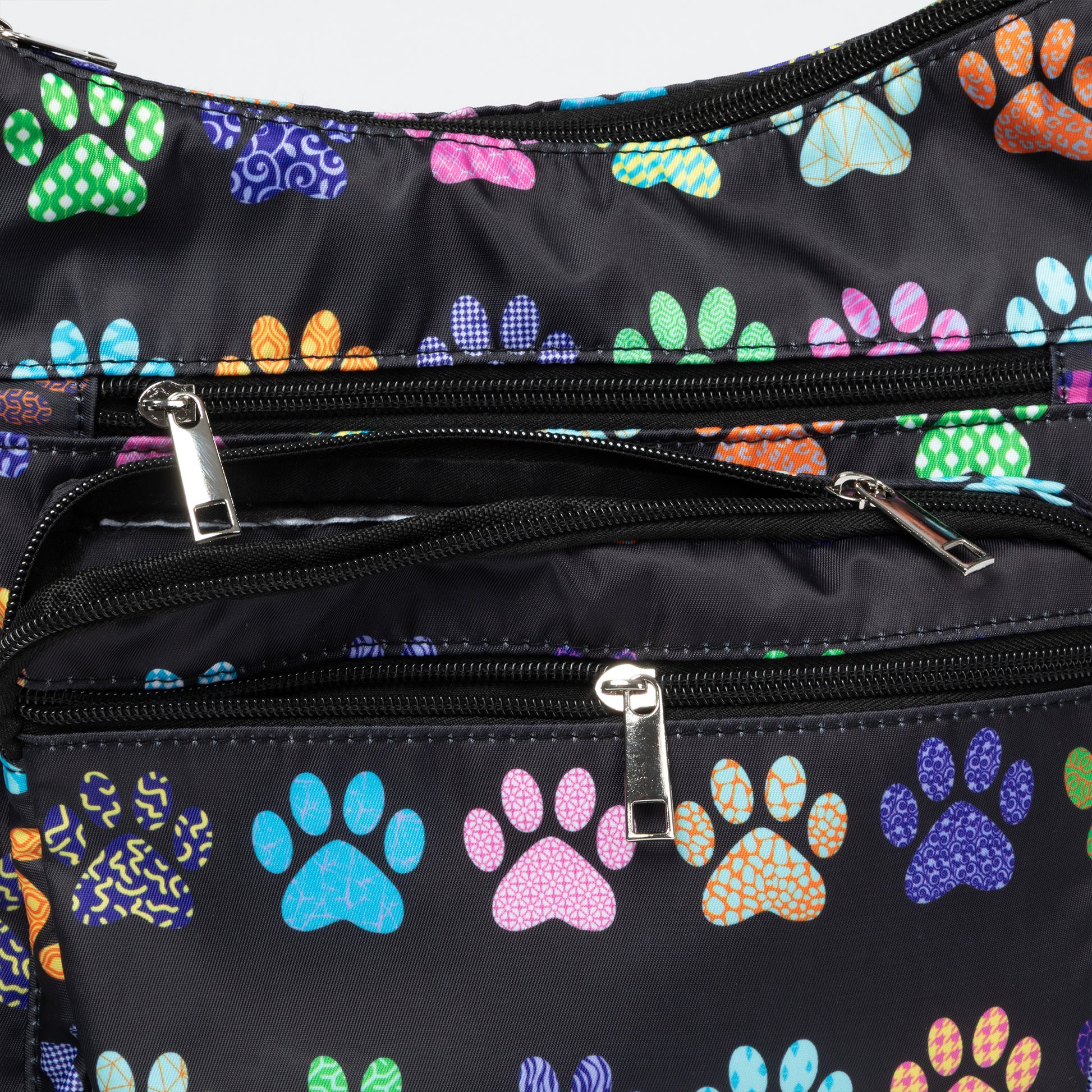 Close-up of a black nylon backpack or bag with multiple zippered pockets and a colorful paw print pattern in green, blue, pink, orange, and purple.