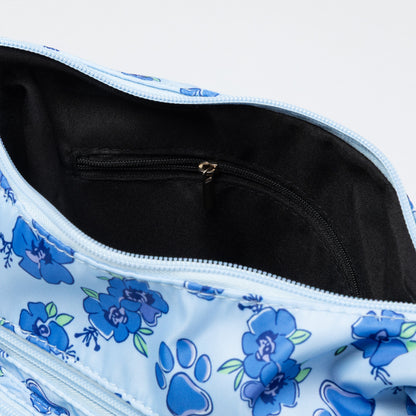 Close-up of a light blue and white floral bag with blue paw prints, showing a black interior zippered pocket.