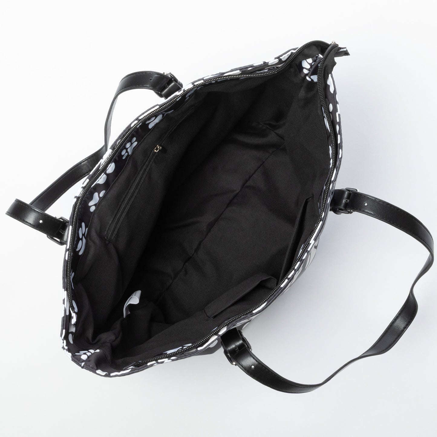 Black tote bag with white paw prints, viewing the interior lining with pockets.