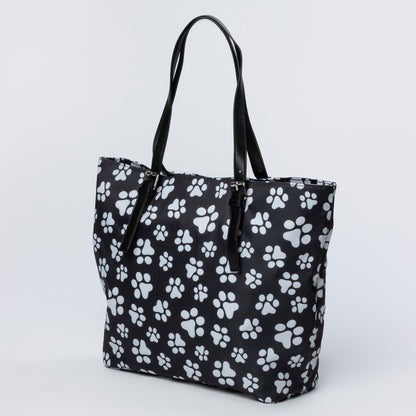 Black tote bag with white paw print pattern on a light gray background