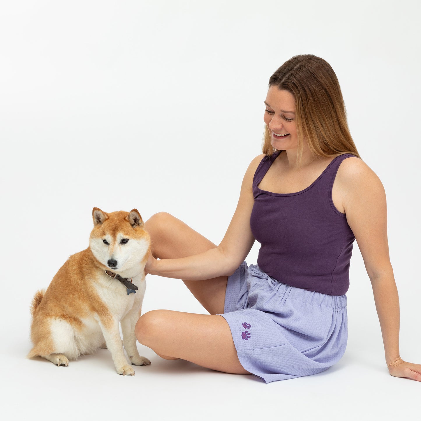 Woman sitting on the floor with a Shiba Inu dog on a white background