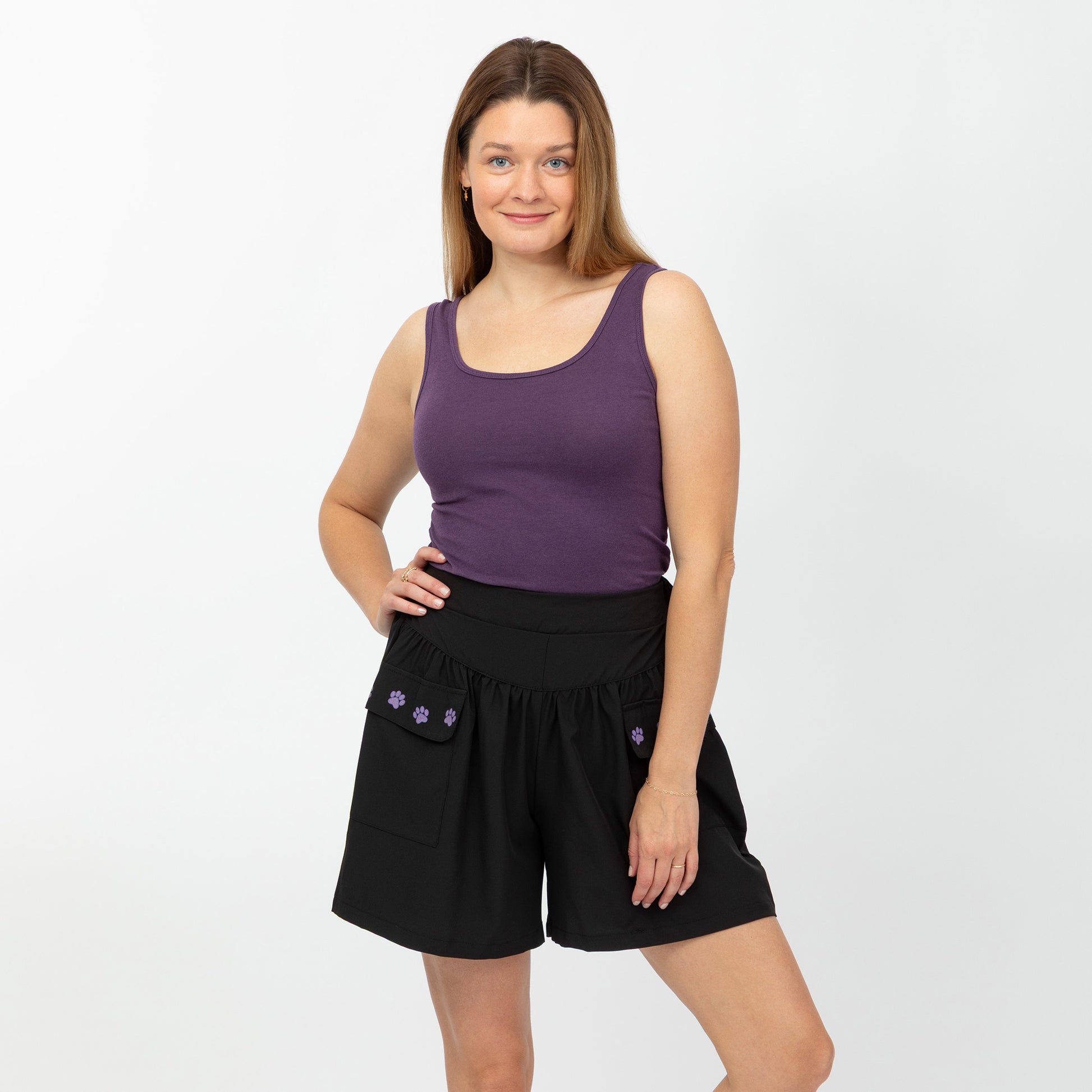 Woman wearing a purple tank top and black shorts on a white background