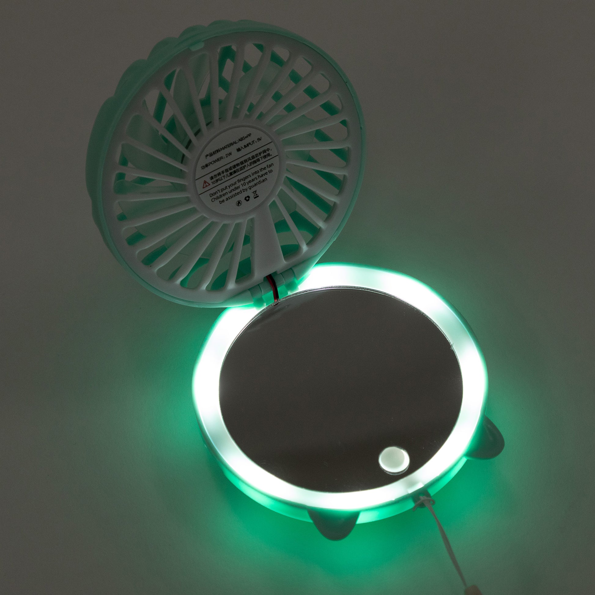 A circular wall-mounted fan and LED light mirror combo, shown open with the fan visible on the upper half and a glowing green LED ring around a mirror on the lower half.