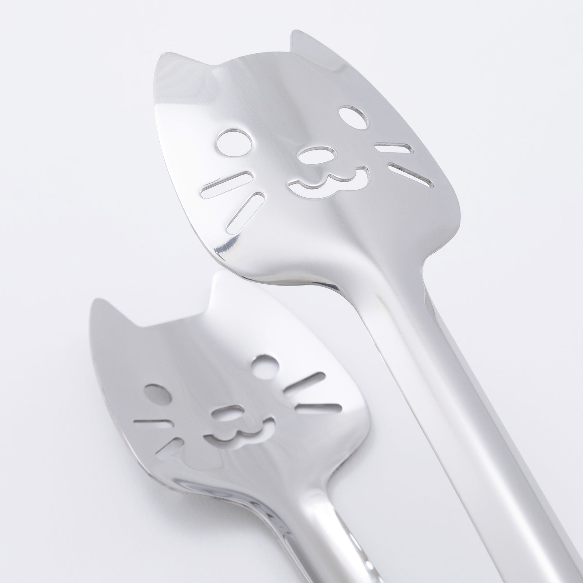 Two cat-shaped utensils on a light gray background