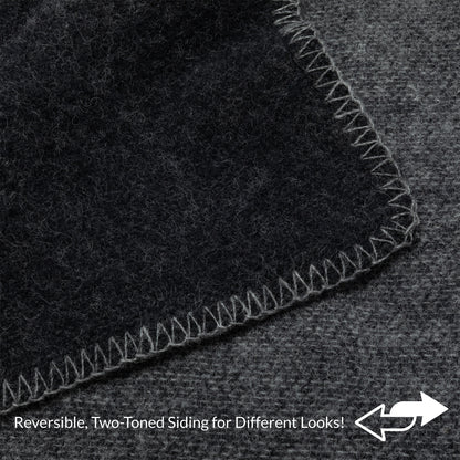Close-up of a dark charcoal gray textured material with a lighter gray stitched border, showing a reversible two-toned side feature with text overlay at the bottom.