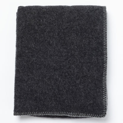 A folded dark charcoal gray merino wool blanket with a visible zigzag stitched edge, shown on a plain white background.