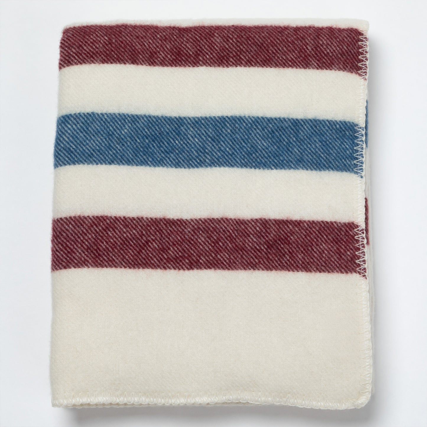 A folded striped wool blanket with horizontal bands of cream, blue, and burgundy red, shown on a clean white background.