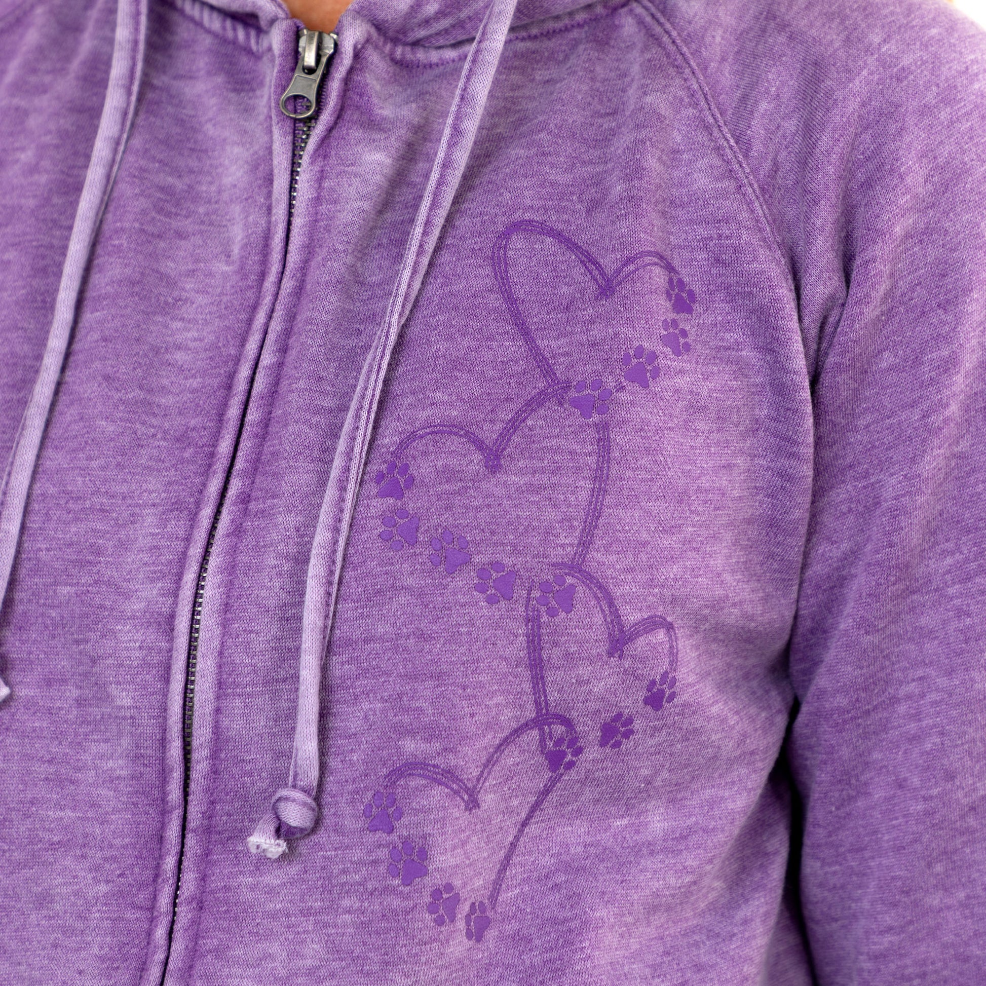 Close-up of a heather purple zip-up hoodie with a tonal purple graphic of connected hearts and paw prints on the chest.