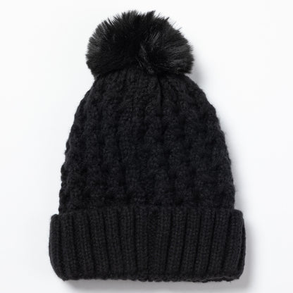A black cable-knit beanie with a matching black faux fur pom-pom on top, shown against a plain white background.