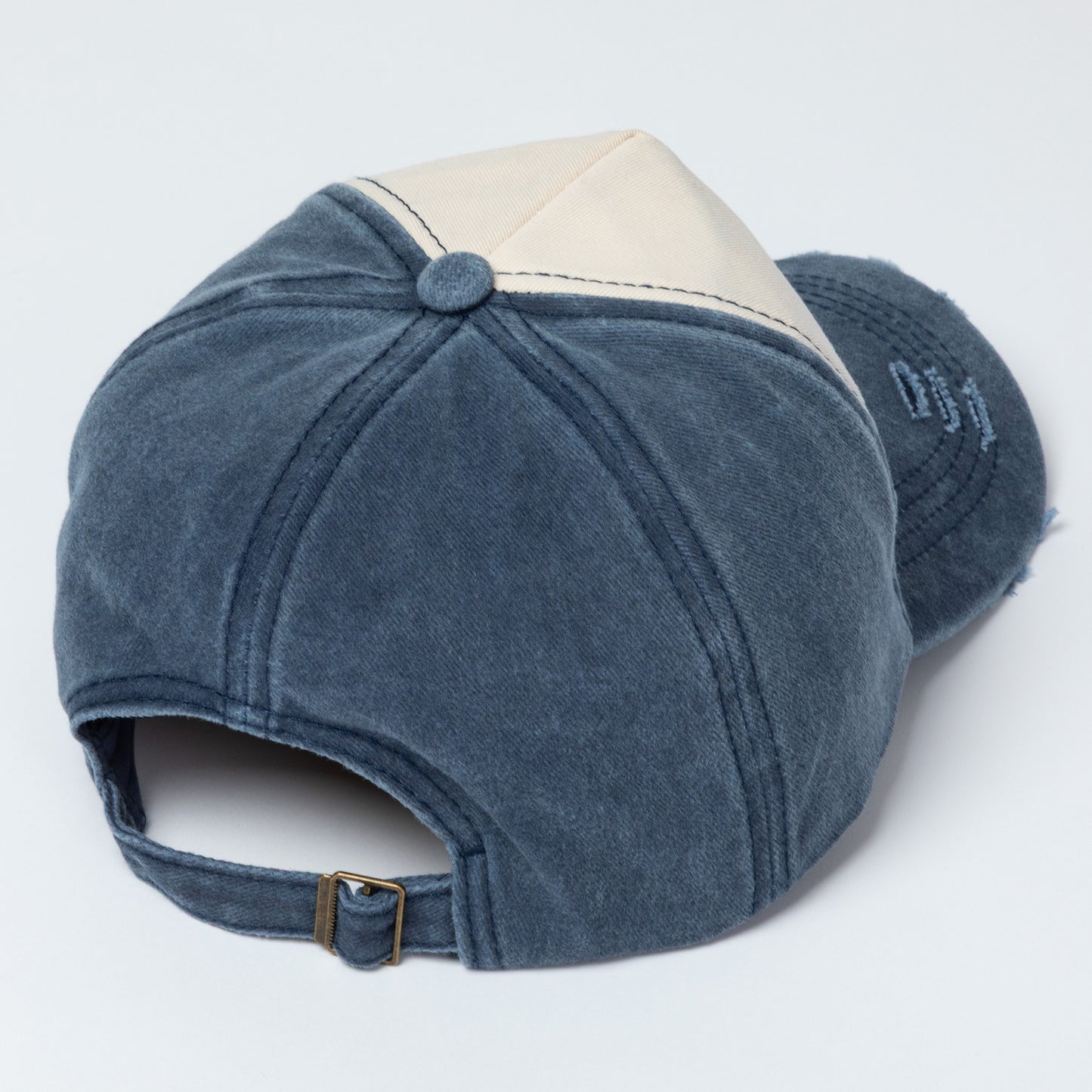Blue baseball cap with beige peak on a white background