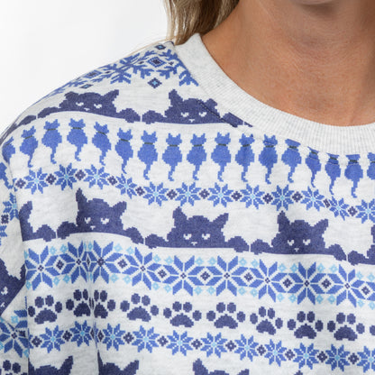 Close-up of a person wearing a knit crewneck sweater with a blue and navy cat-themed Fair Isle pattern on a white background.