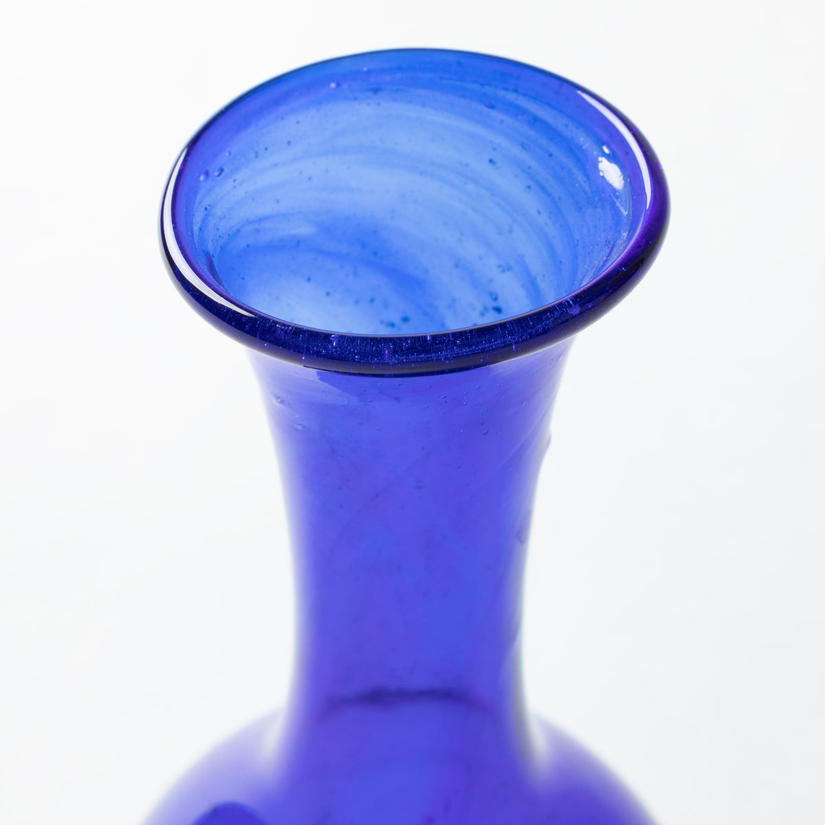 A close-up of a cobalt blue glass vase showing its flared rim and smooth neck against a plain white background.