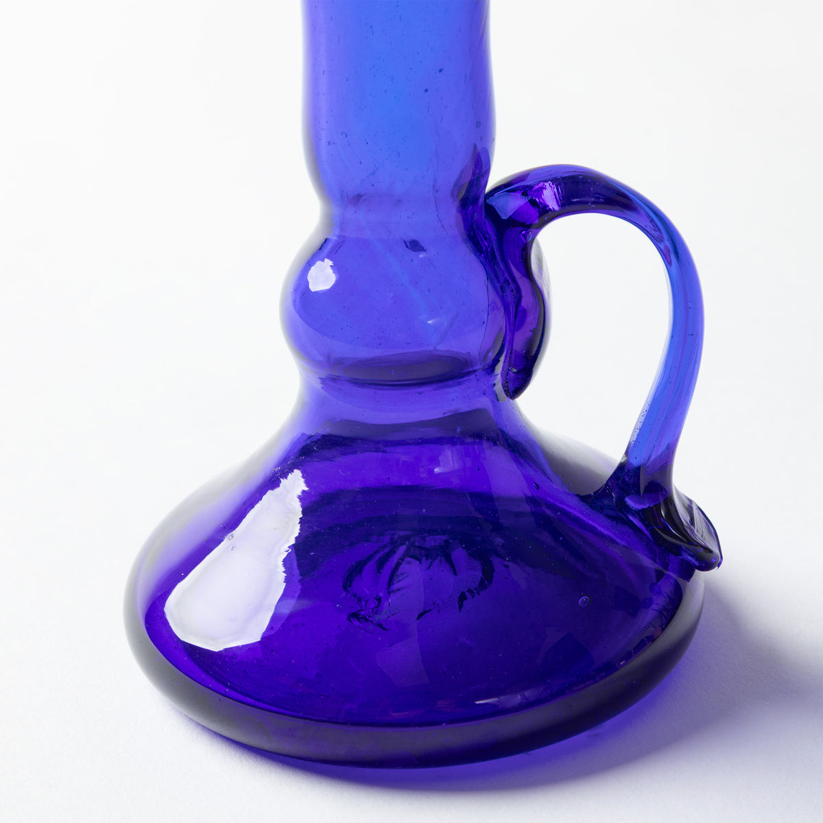 A cobalt blue glass candle holder shown on a white background.