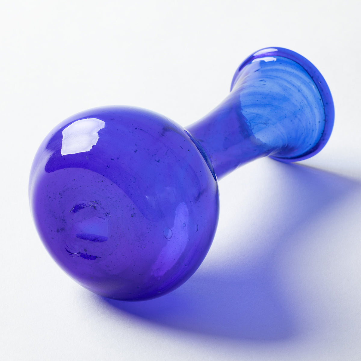 A translucent cobalt blue glass vase, shown on a clean white background with a soft blue shadow.