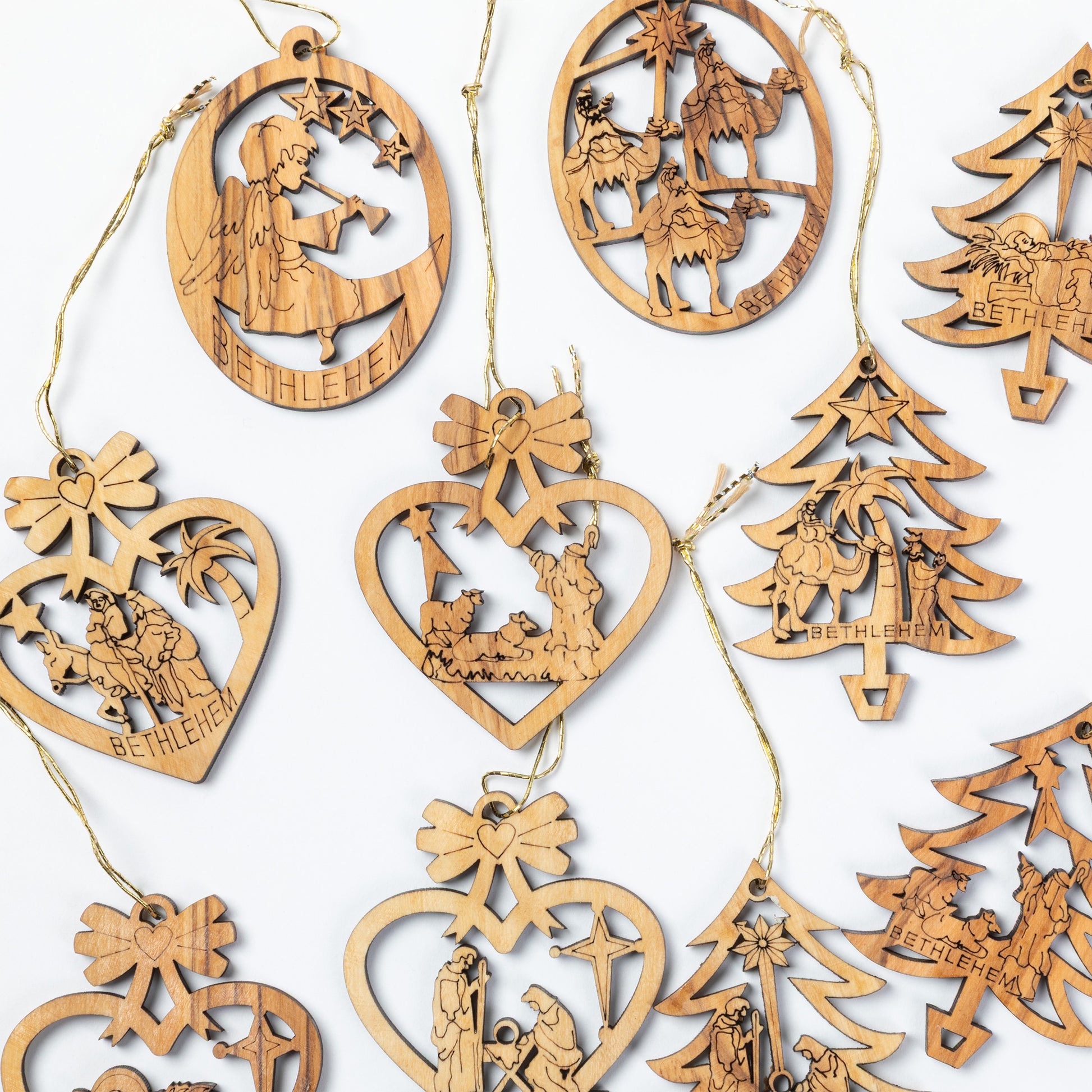 A collection of laser-cut wooden Christmas ornaments in various shapes including hearts, trees, and circles, each featuring engraved nativity scenes and the word 'BETHLEHEM' on a white background.