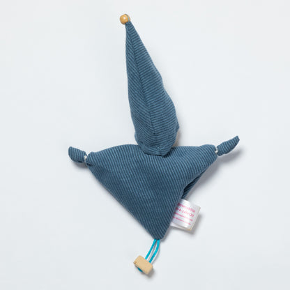 A blue ribbed fabric doll with a wooden pom-pom on the tip of the hat, a wooden pom-pom on the bottom corner, and a small white tag attached.