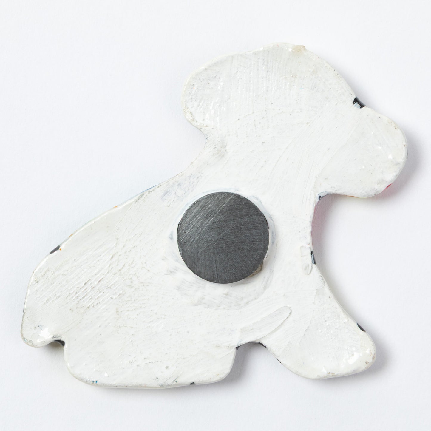 The back of a ceramic dog shaped magnet, against a white background.