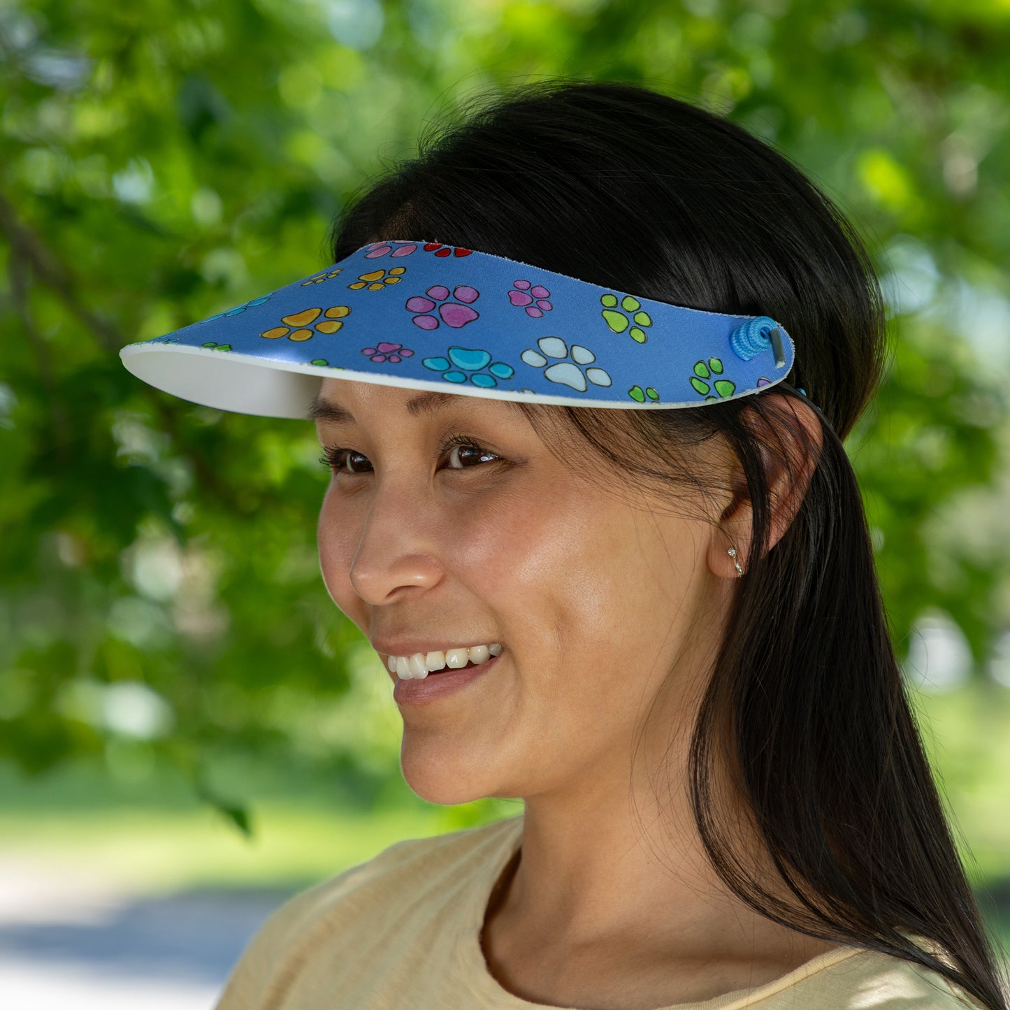 Woman wearing a colorful visor with paw prints outdoors