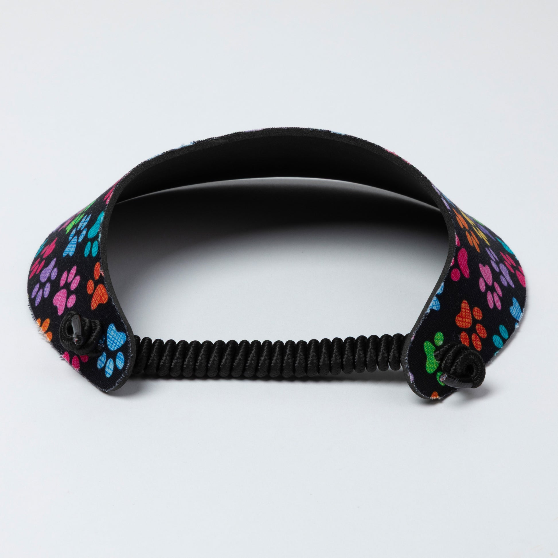 Black visor with colorful paw print design on a light gray background