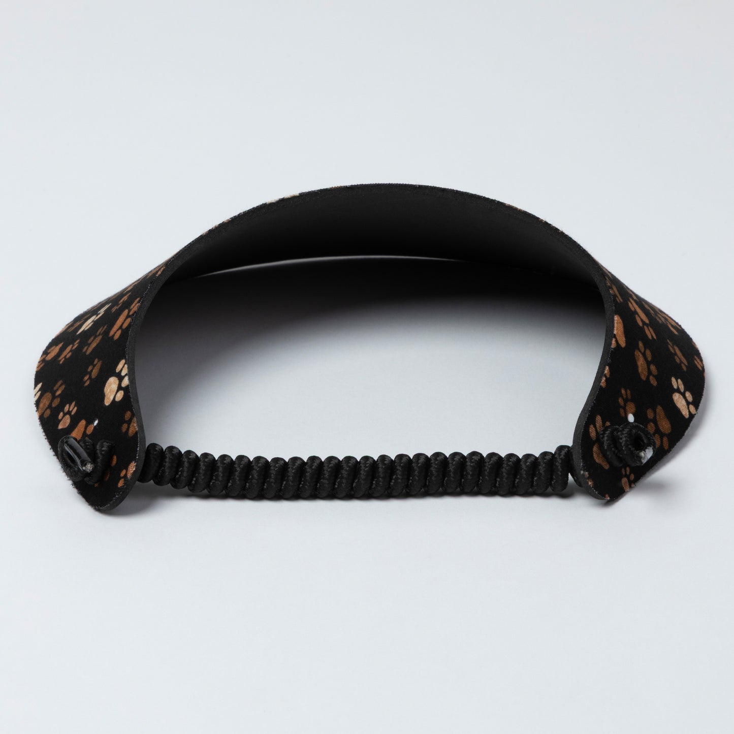 Black visor with a patterned strap on a light gray background