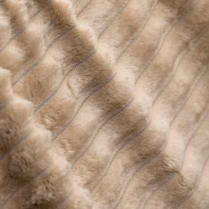 Close-up of a plush faux fur or sheepskin-style textile in a warm beige/taupe tone with subtle stitched vertical channeling.
