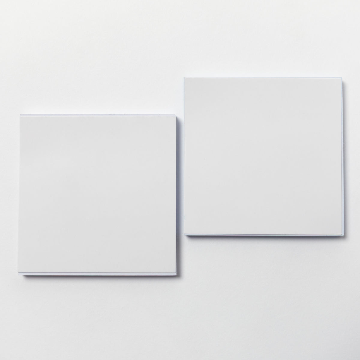 Two blank white square cards or sheets of paper arranged side by side on a clean white background.