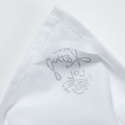 Close-up of a white dish towel with text on a light gray background