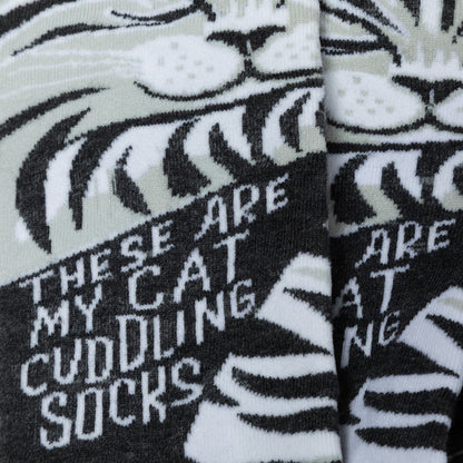 Black and white cat with stripes with text 'These are my cat cuddling socks' on a white background