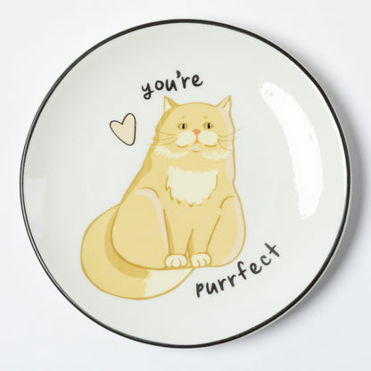 A round white ceramic plate with a black rim, featuring a cute illustration of a yellow-orange cat with the text 'you're purrfect' and a small heart.
