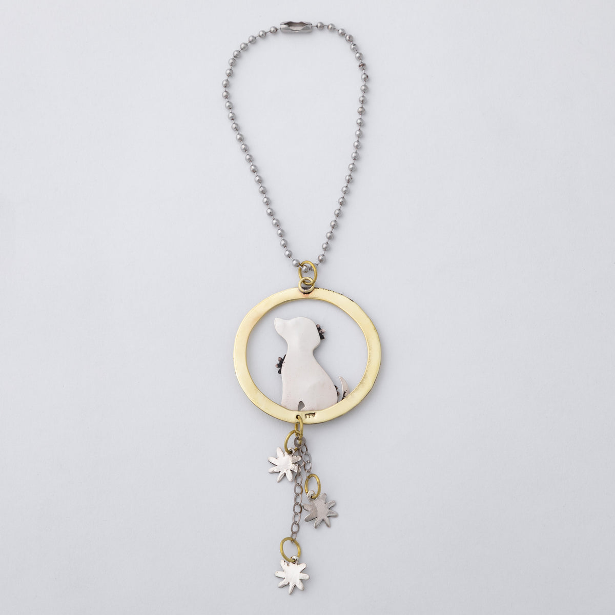 A silver and brass car charm featuring a circular pendant with a gold-toned ring, a silver dog silhouette, and dangling flower charms, shown on a light gray background.