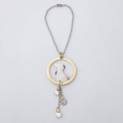 A silver and brass car charm featuring a circular pendant with a gold-toned ring, a silver dog silhouette, and dangling flower charms, shown on a light gray background.