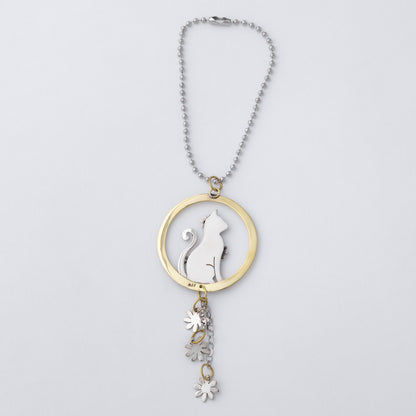A silver ball chain car charm featuring a circular pendant with a silver cat silhouette and flower details, accented by a gold-tone ring and matching dangling flower charms, shown on a light gray background.