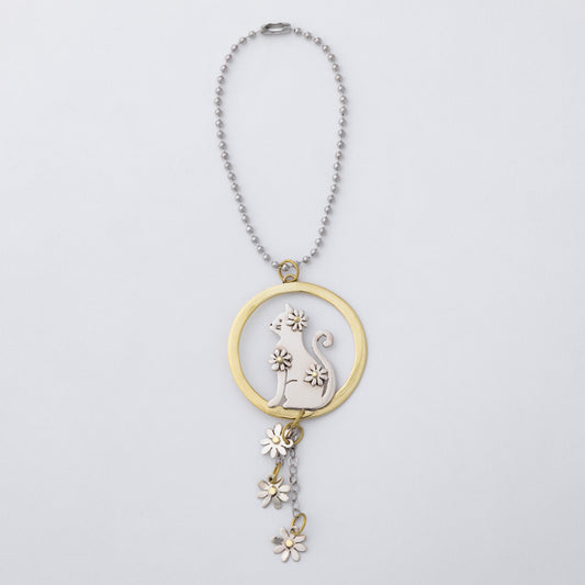 A silver ball chain car charm featuring a circular pendant with a silver cat silhouette and flower details, accented by a gold-tone ring and matching dangling flower charms, shown on a light gray background.