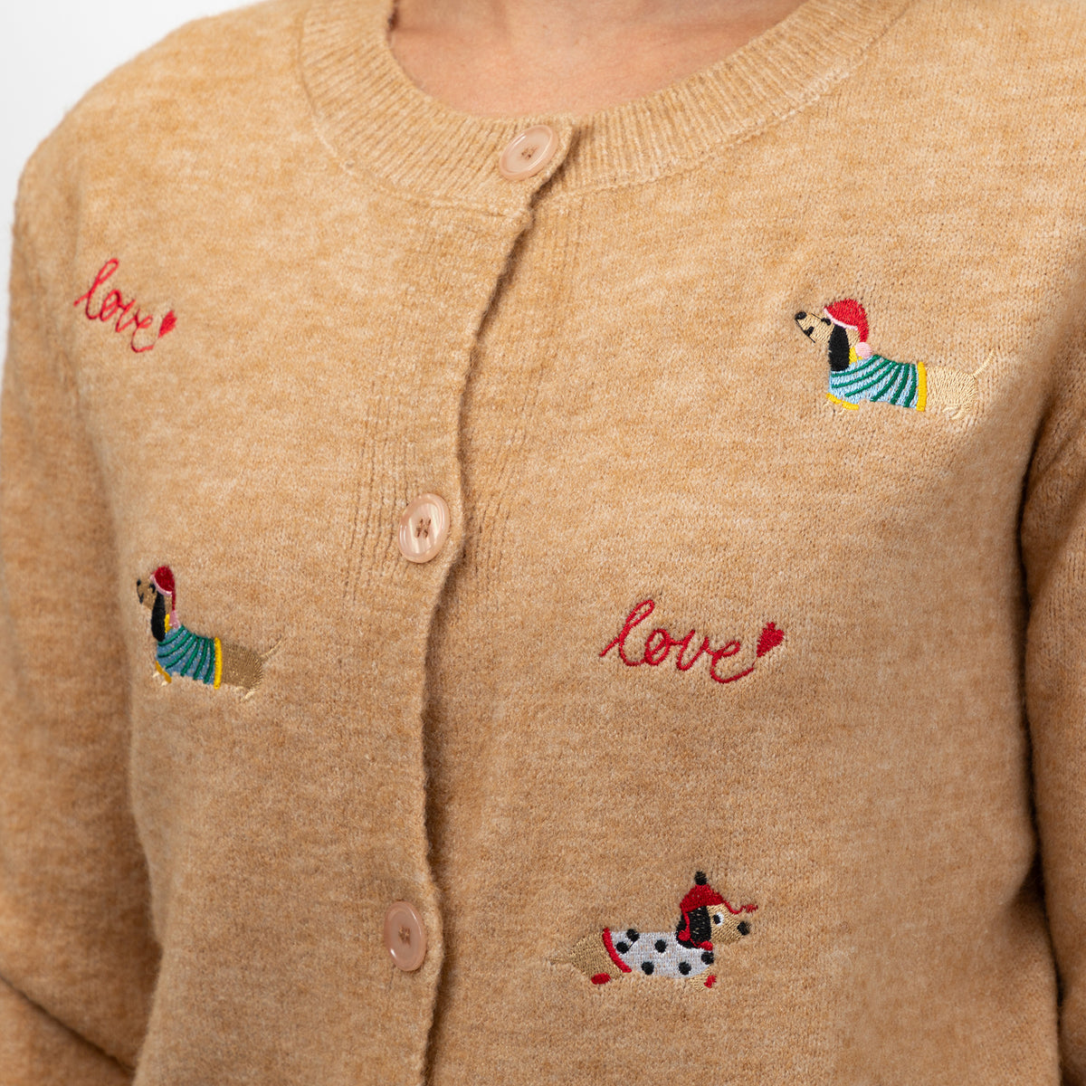 Close-up of a beige knit cardigan sweater with pink embroidered 'love' text and small colorful dachshund motifs on the front.