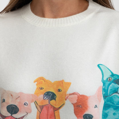 Close-up of a white crewneck sweater featuring a colorful graphic print of cartoon dogs, worn by a model.