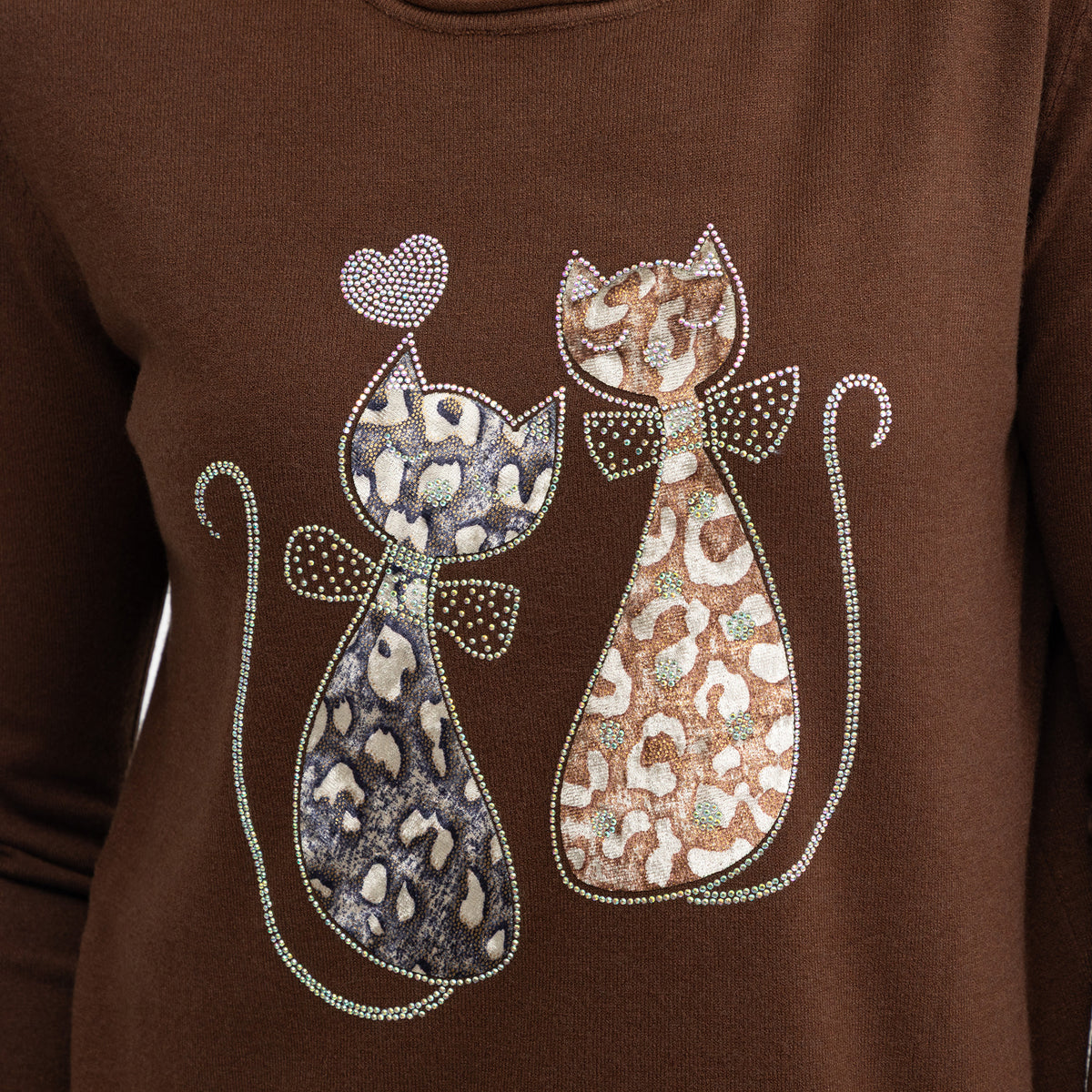 A close-up of a brown long-sleeve top featuring a graphic of two stylized cats with leopard and cheetah patterns, embellished with rhinestones, on a solid brown background.