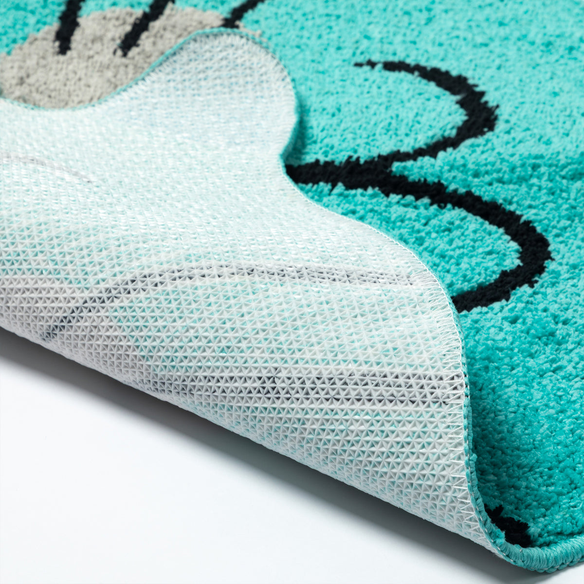 Close-up of a plush rug with a turquoise and white cat-face design, showing the textured pile and the white backing.
