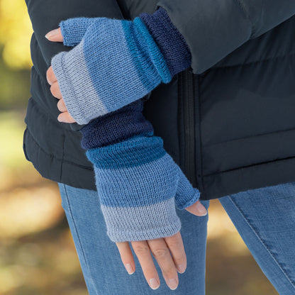 Person wearing blue striped fingerless gloves with a blurred outdoor background