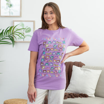 Woman wearing a purple t-shirt with colorful cat illustrations in a living room setting.