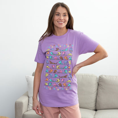 Woman wearing a purple t-shirt with colorful dogs, standing in a room with a light-colored couch.