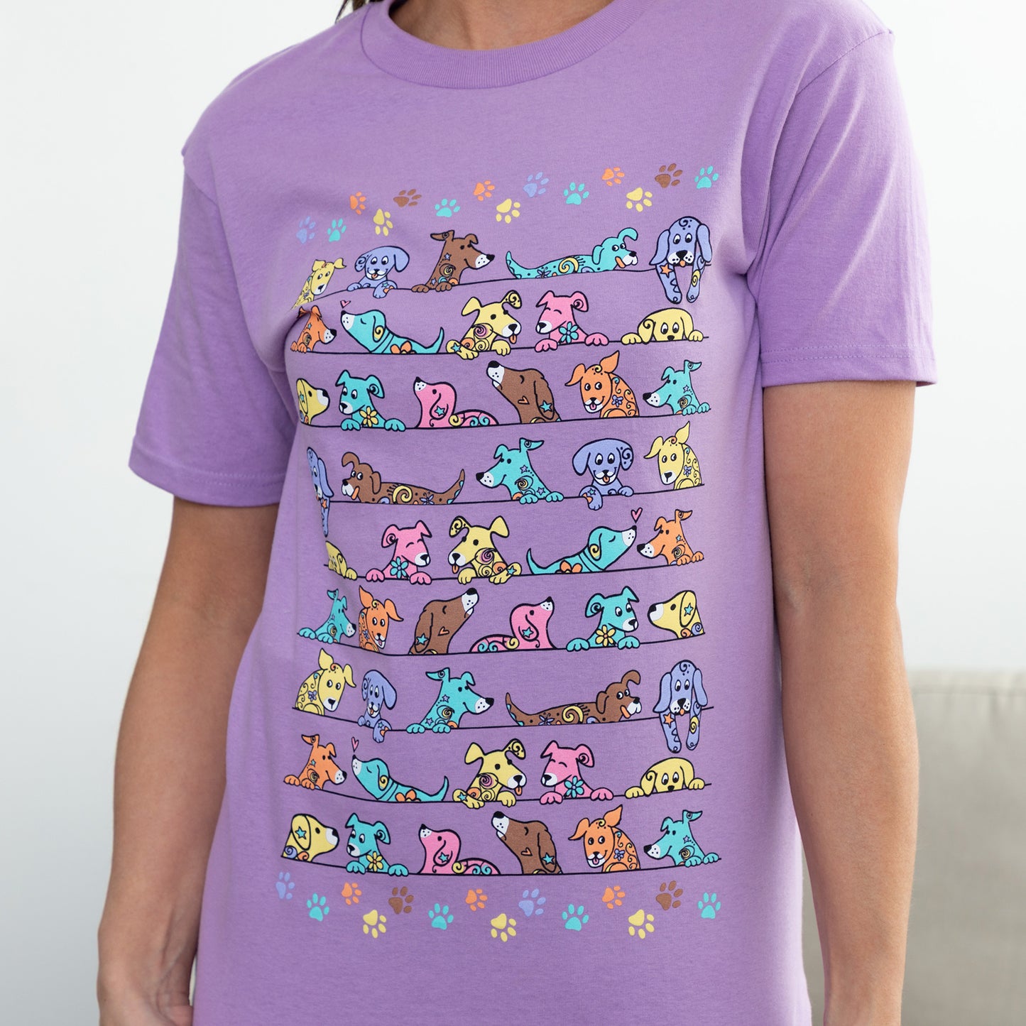 Purple t-shirt with colorful dog illustrations on a plain background