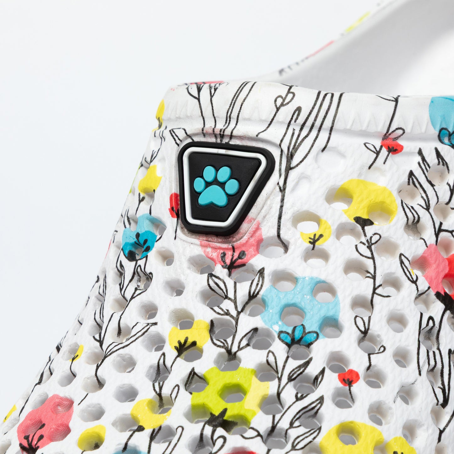 Close up of a clog with floral pattern and paw print design on a white background
