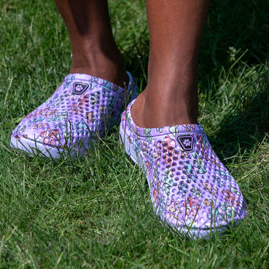 Purple clogs with floral pattern worn on grass