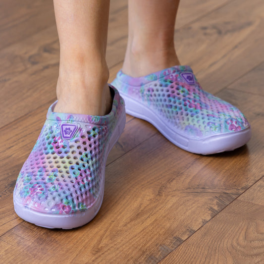 Colorful, breathable clogs worn by a person on wooden flooring.
