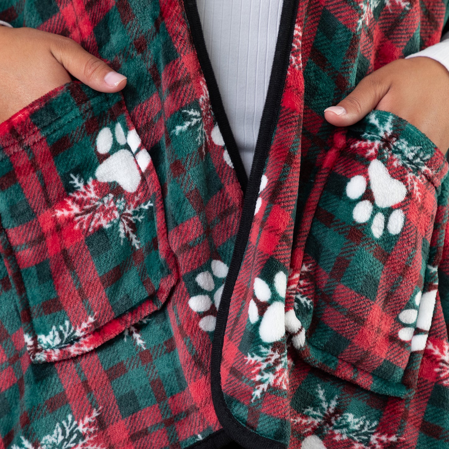 Hands in the two pockets of the wearable blanket shawl. The warm, soft fleece is visible along with the elegant black piping. 