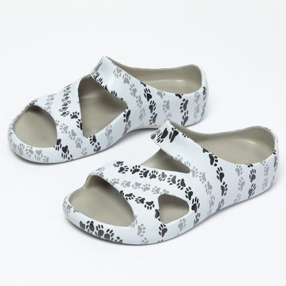 White sandals with black paw print pattern on a white background